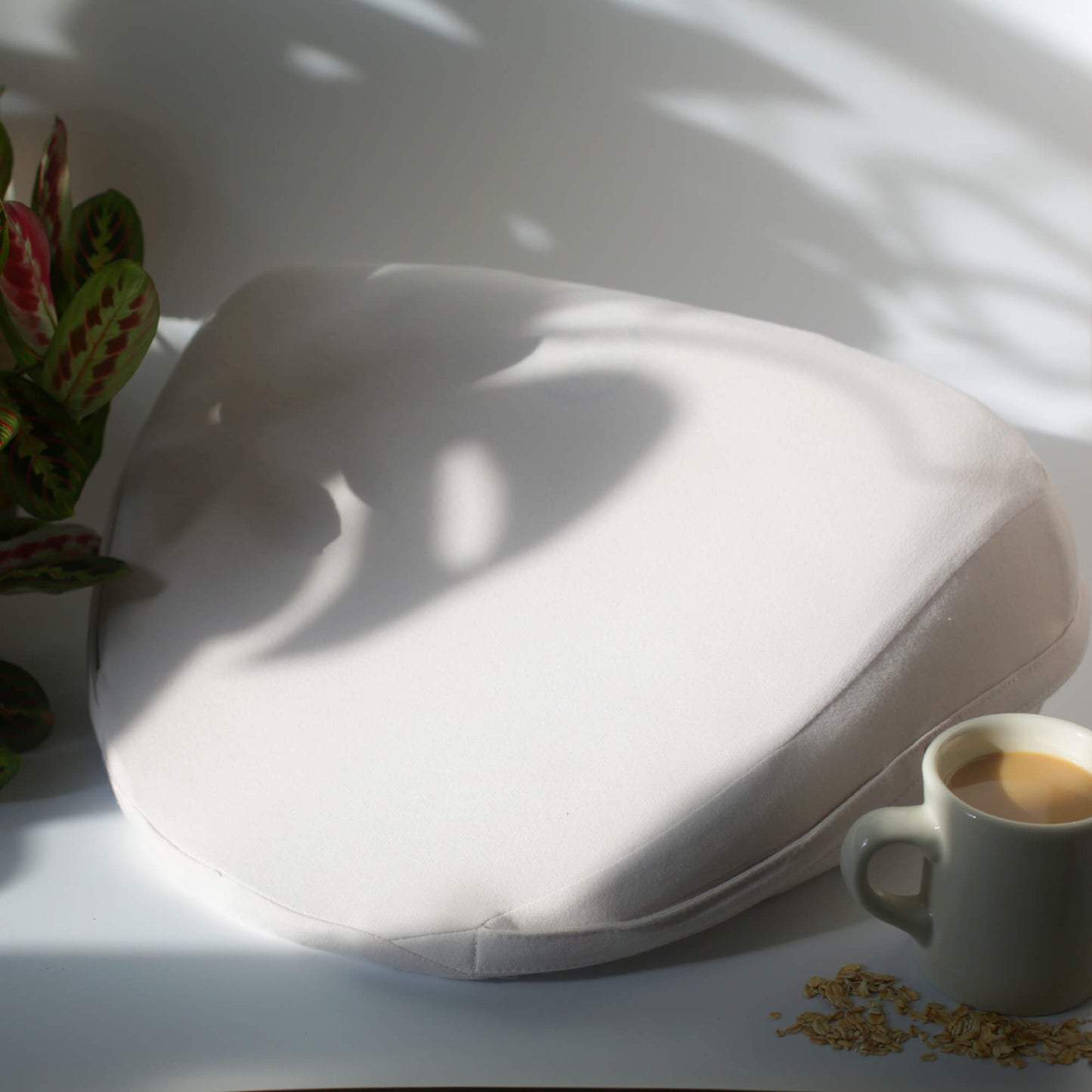 Oat | Oat White Pillo on a table under the sun light next to a coffee cup