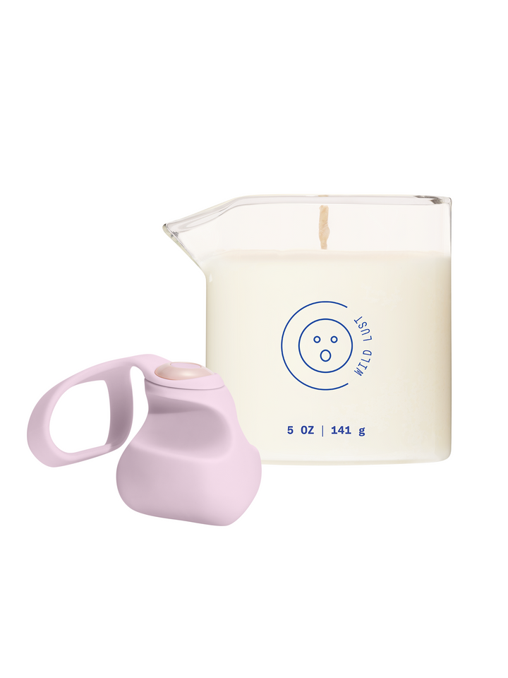 Finger vibrator Fin in light pink next to massage oil candle in Wild Lust on a white background.
