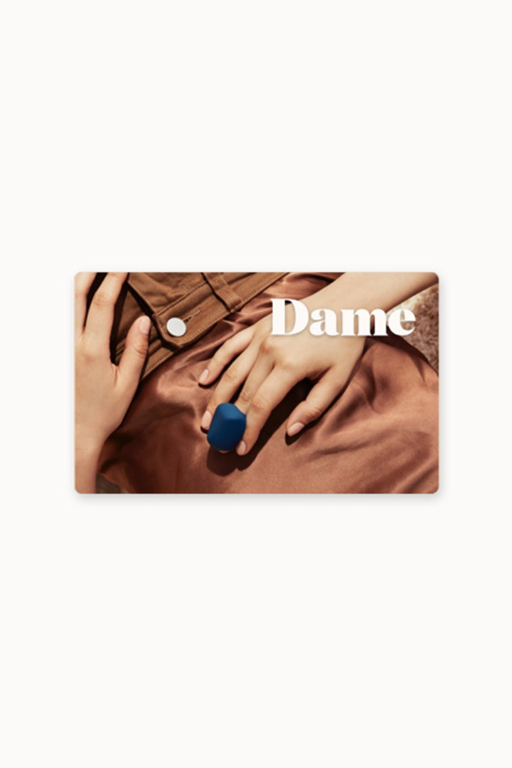 Gift-Card | A rectangular, gift card with Dame's logo in white in the center over top a photo of a woman's hand with Fin in Navy.