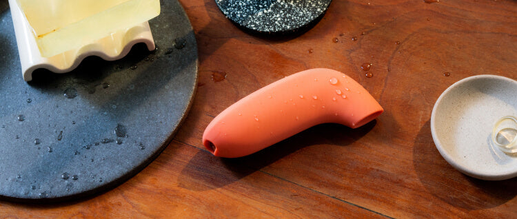 Dame's Aer vibrator in orange on a table