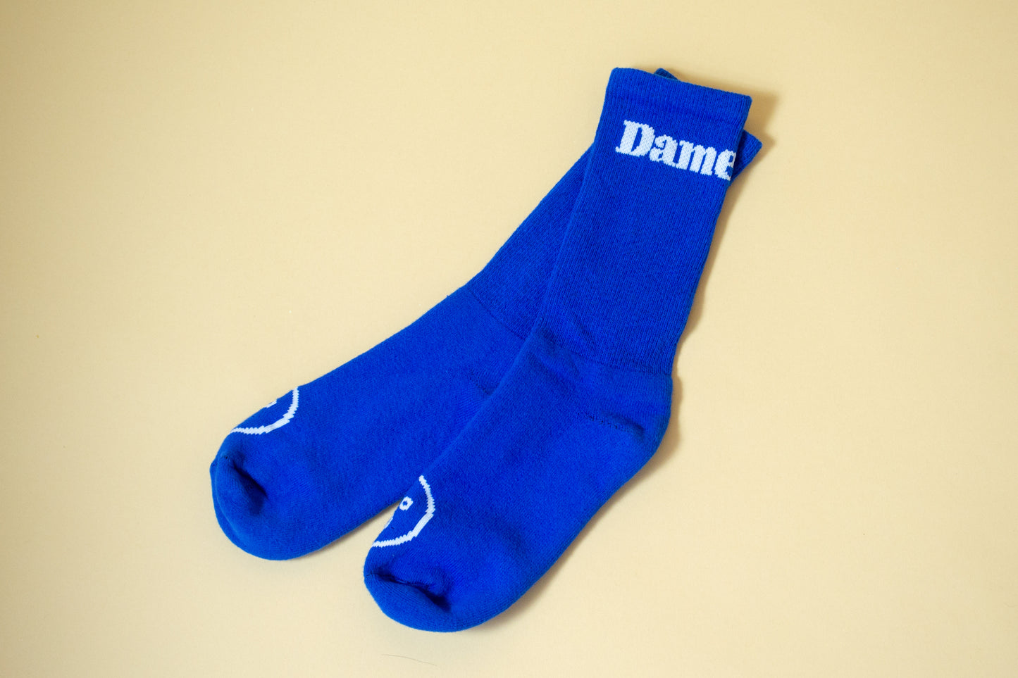 Dame Socks | A pair of bright blue Dame Socks on beige background