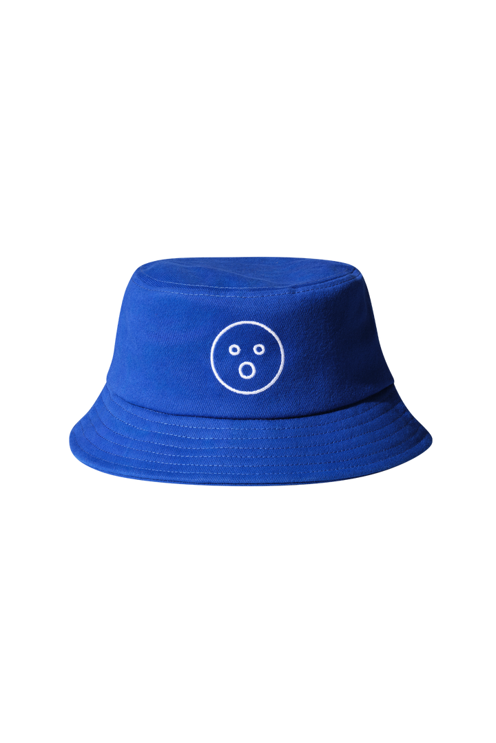 | A royal blue bucket hat with Dame's O-face embroidered onto it in white. Beige background.