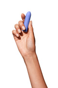 Periwinkle | Simple blue bullet vibrator Zee on nightstand with model's left hand reaching for Zee